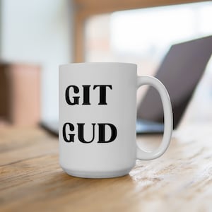 Puede incluir: Taza de café de cerámica blanca con texto negro que dice "GIT GUD".