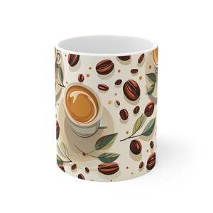 Könnte beinhalten: Eine weiße Keramiktasse mit einem Muster aus Kaffeebohnen, Blättern und einer Tasse Kaffee. Die Tasse hat einen cremefarbenen Hintergrund mit braunen Kaffeebohnen und grünen Blättern.