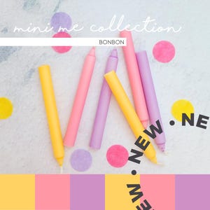 Könnte beinhalten: Fünf bunte Kerzen in Gelb, Rosa und Lila auf einem weißen Hintergrund mit Konfetti angeordnet. Der Text "mini me collection BONBON" befindet sich oben im Bild. Der Text "NEW" ist schräg in schwarzen Buchstaben auf der rechten Seite des Bildes geschrieben.