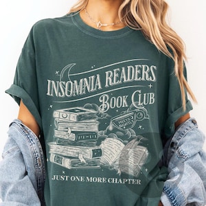 May include: A teal green t-shirt with a white graphic design featuring a stack of books and the text "Insomnia Readers Book Club" and "Just One More Chapter".