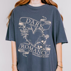 Op de afbeelding: Een donkerblauw oversized T-shirt met een grafische print van een hart met doornen, schedels en een banner met de tekst "DARK ROMANCE always falling for the villain".