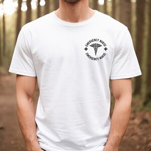 May include: White t-shirt with a black and white graphic of a medical symbol and the text "Emergency Nurse" on the front.