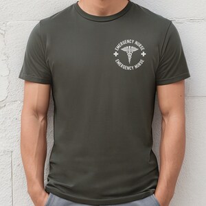 May include: A dark green t-shirt with a white circle graphic featuring a caduceus symbol and the text "Emergency Nurse" repeated twice.