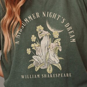 May include: A green t-shirt featuring a vintage illustration of three women in a garden with the text "A Midsummer Night's Dream" and "William Shakespeare".