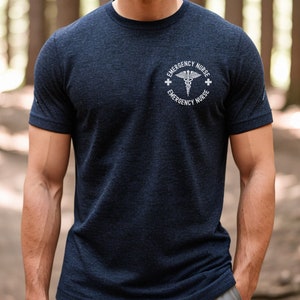 May include: A navy blue t-shirt with a white graphic of a medical symbol and the text "Emergency Nurse" on the front.