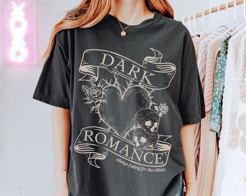 Op de afbeelding: Zwart T-shirt met een grafische print van een hart met doornen, schedels en een banner met de tekst "DARK ROMANCE always falling for the villain".