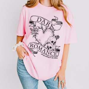 Op de afbeelding: Roze oversized T-shirt met een zwarte grafische print van een hart met doornen, twee schedels en een banner met de tekst "DARK ROMANCE always falling for the villain".