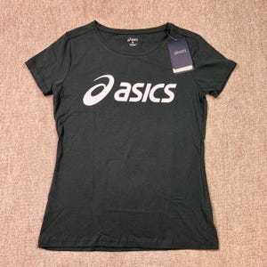 Peut inclure: T-shirt vert foncé avec le logo "asics" blanc sur la poitrine. Le t-shirt a des manches courtes et un col rond. Une étiquette avec le logo "asics" est attachée à l'encolure. Le t-shirt est fait d'une matière douce.