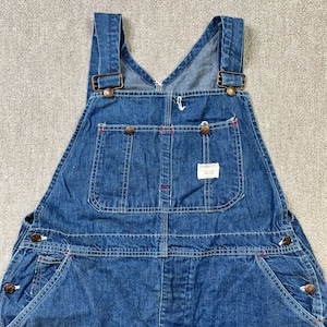 May include: A pair of blue denim overalls with adjustable straps and multiple pockets. The overalls have a classic workwear style.