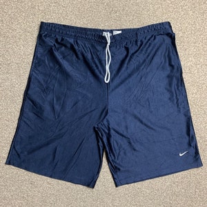 Może przedstawiać: Męskie spodenki sportowe w kolorze granatowym ze sznurkiem do ściągania w kolorze białym i białym logo Nike na prawej nogawce.