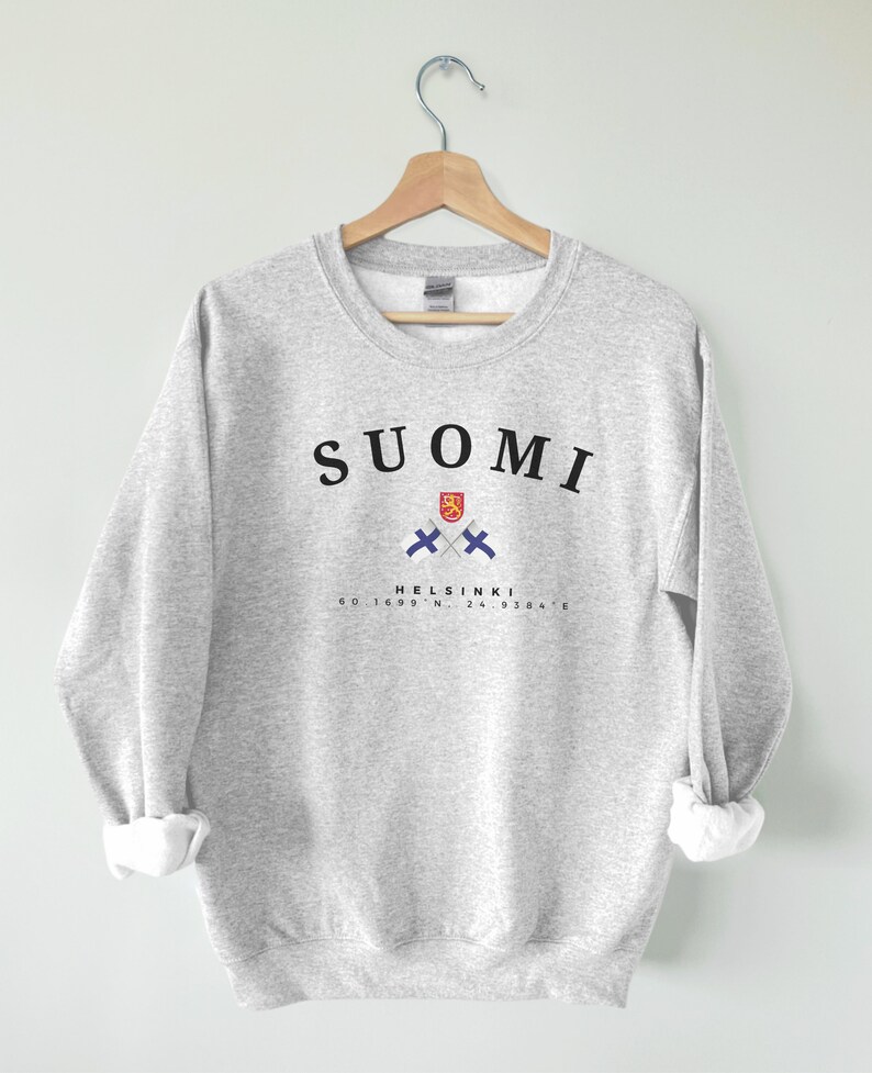 以下が含まれることがあります： グレーのトレーナーに、黒い文字で「SUOMI」と書いてあり、フィンランドの国旗が交差したデザインと、黒い文字で「HELSINKI 60.1699&deg; N, 24.9384&deg; E」と書いてあります。