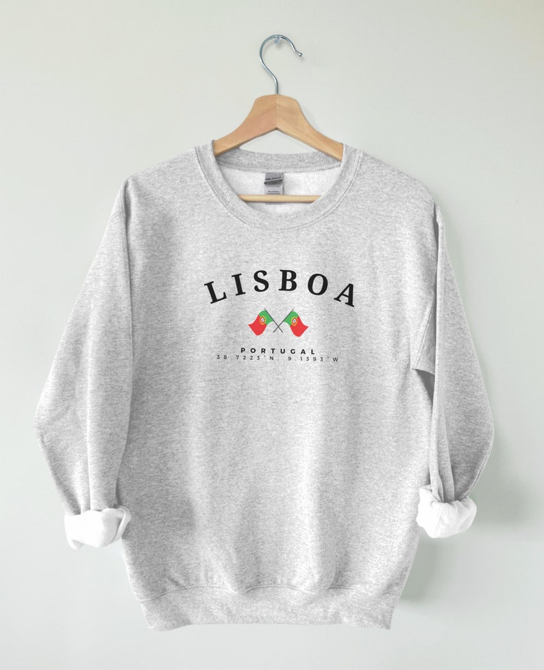 May include: Grey sweatshirt with the text "LISBOA" in black, two crossed Portuguese flags, and the text "PORTUGAL 38.7223&deg;N 9.1393&deg;W" in black.