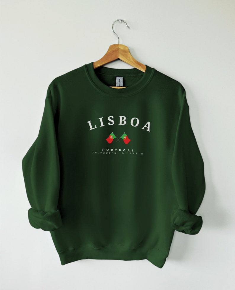 May include: A dark green sweatshirt with the word "LISBOA" printed in white on the front. Below the word is a small image of two crossed Portuguese flags and the text "PORTUGAL 38.7225&deg;N, 9.1393&deg;W".
