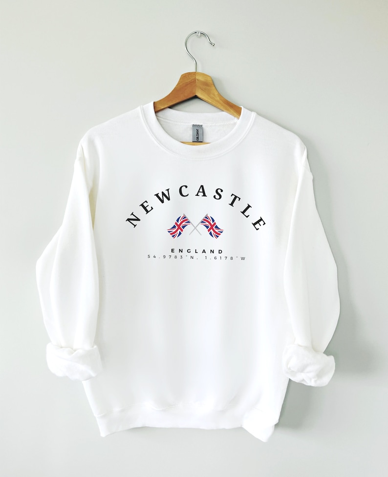 May include: White sweatshirt with a black graphic print that says "NEWCASTLE ENGLAND 54.9783&deg; N 1.6178&deg; W" with two crossed British flags.