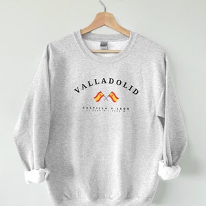 May include: Grey sweatshirt with the text "VALLADOLID" in black, with two crossed Spanish flags and the text "CASTILLA Y LEON 41.6520°N 4.7240°W" below.