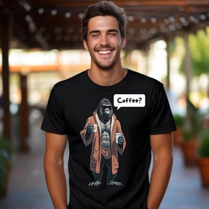 May include: A black t-shirt with a graphic of a gorilla wearing a robe and holding a cup of coffee. The gorilla is saying "Coffee?" in a speech bubble.