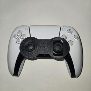 May include: A white PlayStation 5 DualSense controller with a black 3D printed grip attachment.