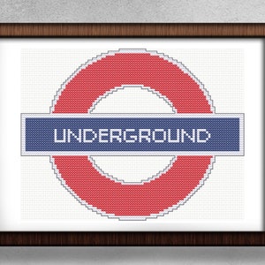 Może przedstawiać: Wzór haftu krzyżykowego w kolorze czerwonym i niebieskim z logo londyńskiego metra, z napisem "UNDERGROUND" na niebieskim pasku.