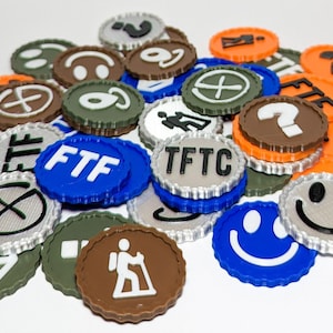 Puede incluir: Una colección de fichas circulares coloridas con varios símbolos y texto. Las fichas son en tonos de azul, naranja, marrón, verde y plateado. Algunas fichas tienen una carita sonriente, un signo de interrogación o las letras "FTF" y "TFTC".