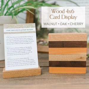 May include: A wooden card display with the text "Wood 4x6 Card Display" and the words "WALNUT • OAK • CHERRY". The display is made of various wood tones and holds a card with the text "COME THOU FOUNT of EVERY BLESSING".