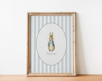 May include: A framed print featuring a watercolor illustration of Peter Rabbit. The artwork is set within an oval on a striped background of light blue and white. The frame is a light brown color. The print includes text at the bottom.