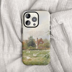 May include: A phone case featuring a pastoral landscape painting with a house, geese, and text. The case has a black border and a glossy finish. The artwork depicts a green field and a red-roofed house.