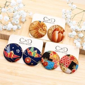 May include: Four pairs of fabric covered button earrings. The earrings feature a variety of Japanese inspired patterns, including floral, geometric, and origami designs. The earrings are made by Calla x Dilly.