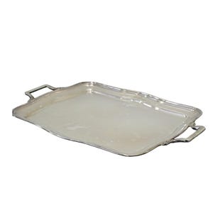 Może przedstawiać: Prostokątna taca do serwowania w kolorze srebrnym z gładką, płaską powierzchnią środkową oraz lekko uniesionym, wyprofilowanym brzegiem. Taca posiada dwa solidne, zintegrowane uchwyty po przeciwległych stronach.