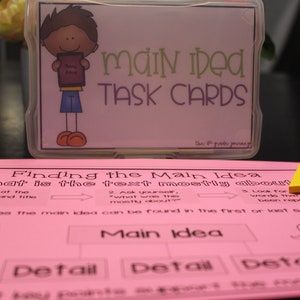 May include: Pink and white printable worksheet with the title "Finding the Main Idea" and instructions on how to find the main idea of a text. The worksheet includes a cartoon character and the words "Main Idea", "Detail", and "Detail".
