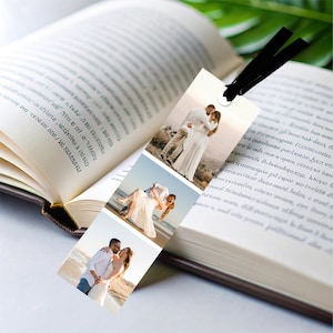 May include: A personalized bookmark featuring three wedding photos, with a black ribbon attached. The bookmark is displayed in an open book with text on the pages. The photos show a couple in wedding attire.
