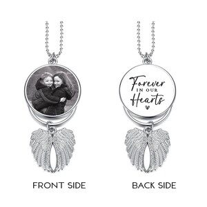 May include: A silver memorial pendant with a chain. The front side features a black and white photo of two children. The back side has the text "Forever in our Hearts" in black script. Below the pendant is a pair of detailed angel wings.