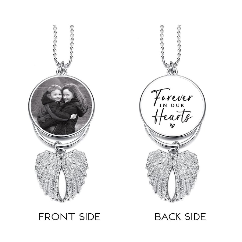 May include: A silver memorial pendant with a chain. The front side features a black and white photo of two children. The back side has the text "Forever in our Hearts" in black script. Below the pendant is a pair of detailed angel wings.