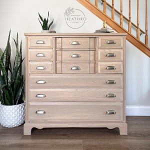 May include: A light wood dresser with multiple drawers and silver handles. The dresser has a simple design and is in a light wood finish.