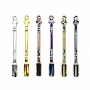 Puede incluir: Seis cucharas pequeñas de metal dispuestas en fila, cada una con un mango ornamentado y un lazo en la parte superior. Las cucharas tienen varios acabados metálicos, incluyendo plata, oro, cobre, arcoíris iridiscente, latón antiguo y gris oscuro.
