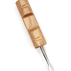 Puede incluir: Una herramienta con mango de madera y una punta de metal afilada y puntiaguda. El mango es marrón y tiene un diseño tallado.