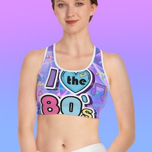 May include: A blue, purple, and pink sports bra with a holographic pattern and the text "I ♥ the 80's" in a retro font.