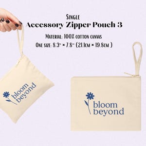 Puede incluir: Bolsa con cremallera para accesorios de lona blanquecina con un dise&ntilde;o floral azul y las palabras "bloom beyond". La bolsa es rectangular, con cierre de cremallera y un asa peque&ntilde;a. Mide 21,1 cm x 19,8 cm.