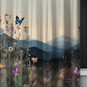 May include: A shower curtain featuring a watercolor-style illustration of a mountain range with a field of wildflowers and butterflies in the foreground. The background is a soft beige color, and the mountains are a deep blue.