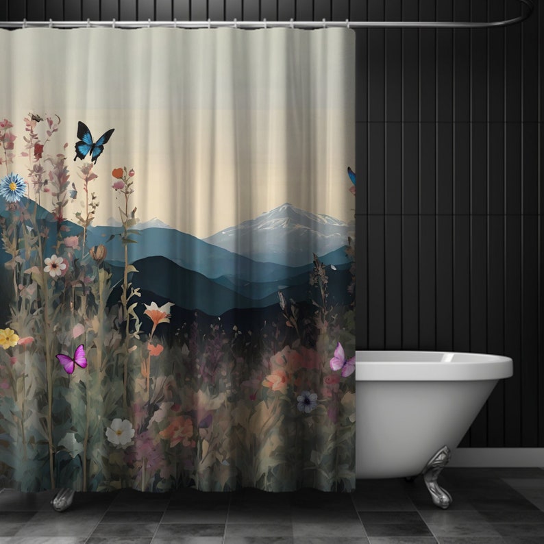 May include: A shower curtain featuring a watercolor-style illustration of a mountain range with a field of wildflowers and butterflies in the foreground. The background is a soft beige color, and the mountains are a deep blue.
