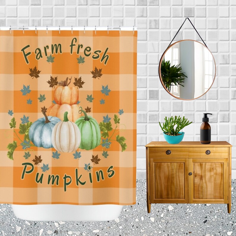 K&ouml;nnte beinhalten: Orange karierter Duschvorhang mit dem Text "Farm fresh pumpkins" und Illustrationen von K&uuml;rbissen und Bl&auml;ttern. Der Duschvorhang befindet sich in einem Badezimmer mit einem Holzschrank, Spiegel und Zubeh&ouml;r.