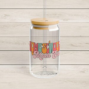 May include: A clear glass can-shaped tumbler with a bamboo lid and a clear straw. The tumbler features the text "Homeschool Mom Ever" in colourful retro-style lettering. The design includes orange, pink, and blue hues.