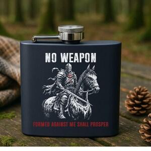 May include: A black stainless steel flask with a silver cap and hinge. The flask features a white illustration of a knight on horseback with the text "NO WEAPON FORMED AGAINST ME SHALL PROSPER" in white and red.