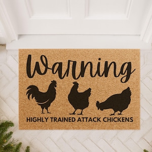 May include: A rectangular doormat made of natural fibers. The mat features the word "Warning" in a cursive font above three black chicken silhouettes. Below the chickens, the text reads "HIGHLY TRAINED ATTACK CHICKENS."