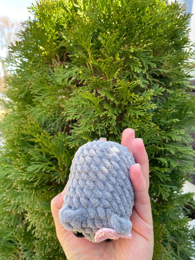 May include: A grey crocheted plush toy shaped like a mouse with pink ears and black eyes.
