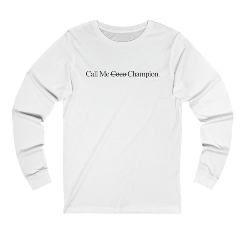 May include: White long-sleeve t-shirt with the text "Call Me Coco Champion." printed on the front.