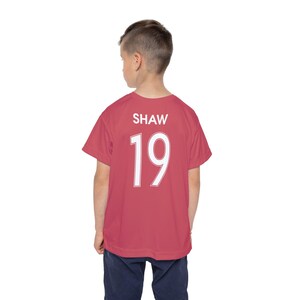 May include: A red soccer jersey with the name "SHAW" and the number "19" printed on the back.
