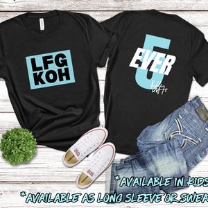 Puede incluir: Dos camisetas negras con texto azul. La primera camiseta dice "LFG KOH" en un cuadro azul. La segunda camiseta dice "EVER" con un gran n&uacute;mero 6 azul. Ambas camisetas est&aacute;n disponibles en tallas para ni&ntilde;os y como manga larga o sudadera.