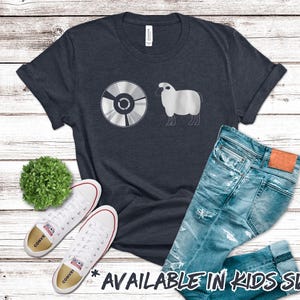 May include: A dark blue t-shirt with a white graphic of a compact disc and a sheep. The text "AVAILABLE IN KIDS SIZES!" is printed below the graphic.