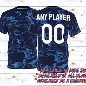 May include: A blue and white camouflage print t-shirt with the text "ANY PLAYER" and the number "00" in white. The shirt is available in kids sizes, all players, and as a sweatshirt.