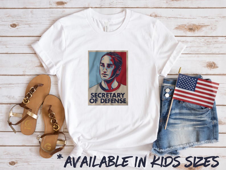May include: White t-shirt with a graphic of a woman's face and the text "Secretary of Defense".
